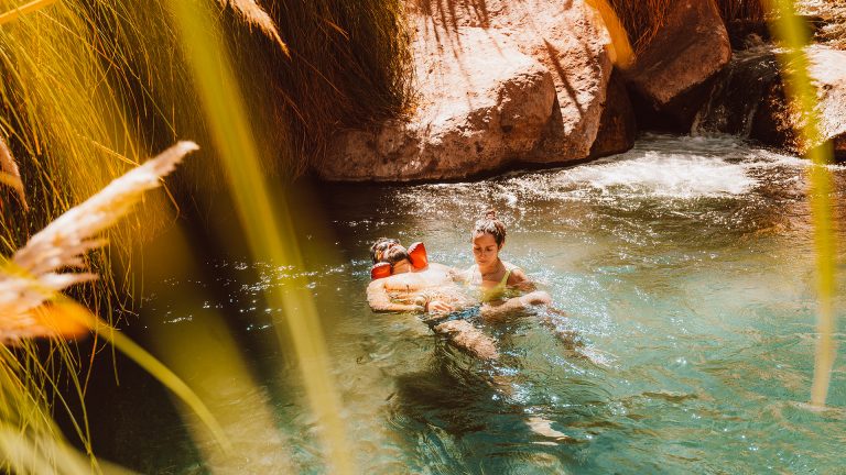 Viajante recebendo massagem watsu nas Termas de Puritama, durante o passeio da FlaviaBia Expediciones