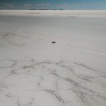 Foto aérea de drone: carro cruzando o Salar de Uyuni.