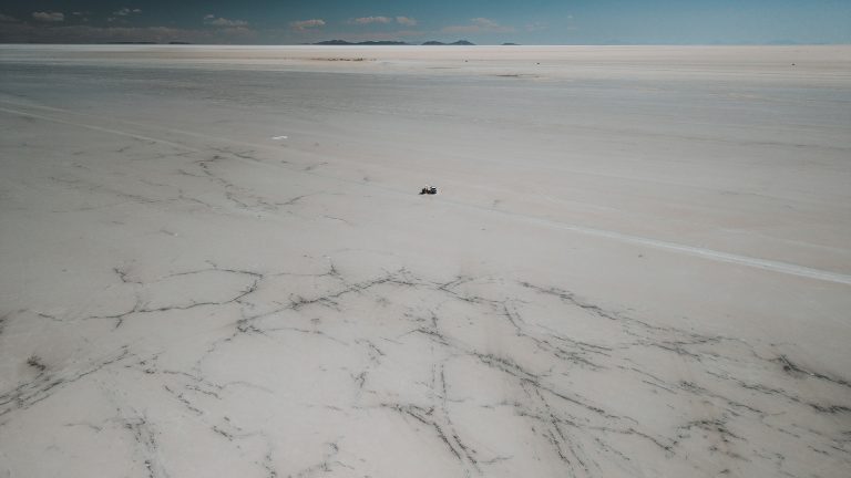 Foto aérea de drone: carro cruzando o Salar de Uyuni.